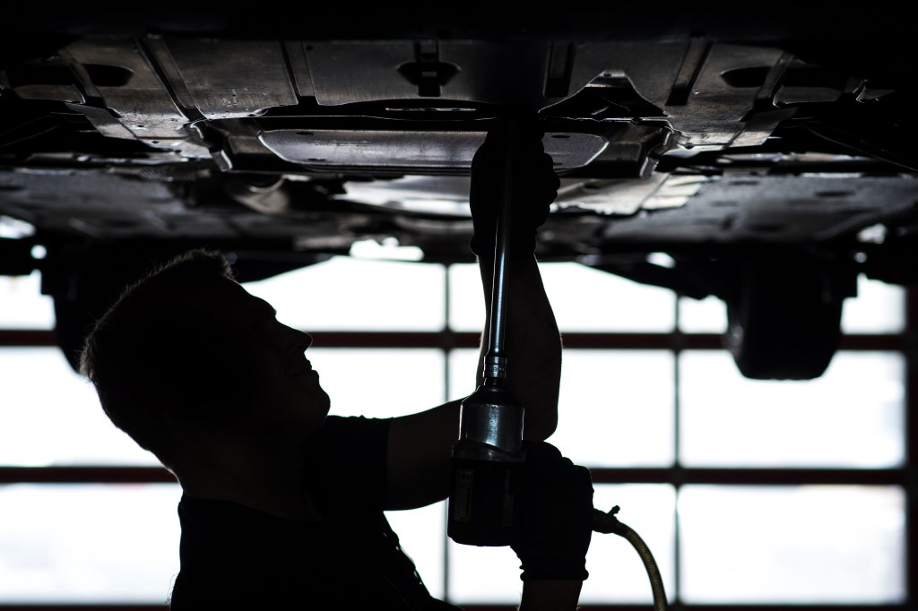 A mechanic works on a car up on a lift