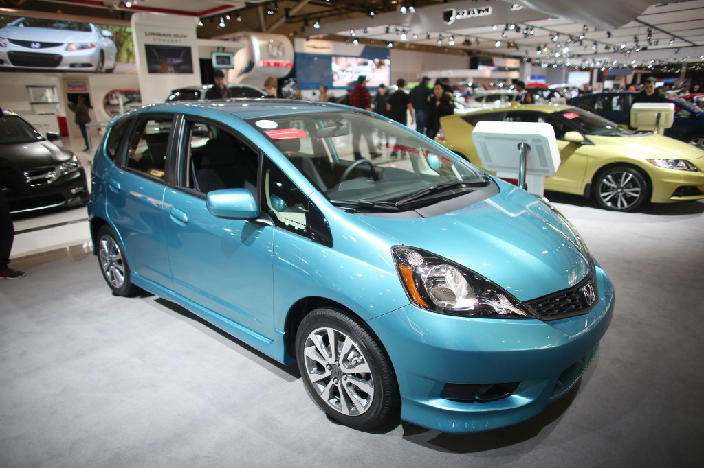 A teal blue Honda fit in the booth at an auto show