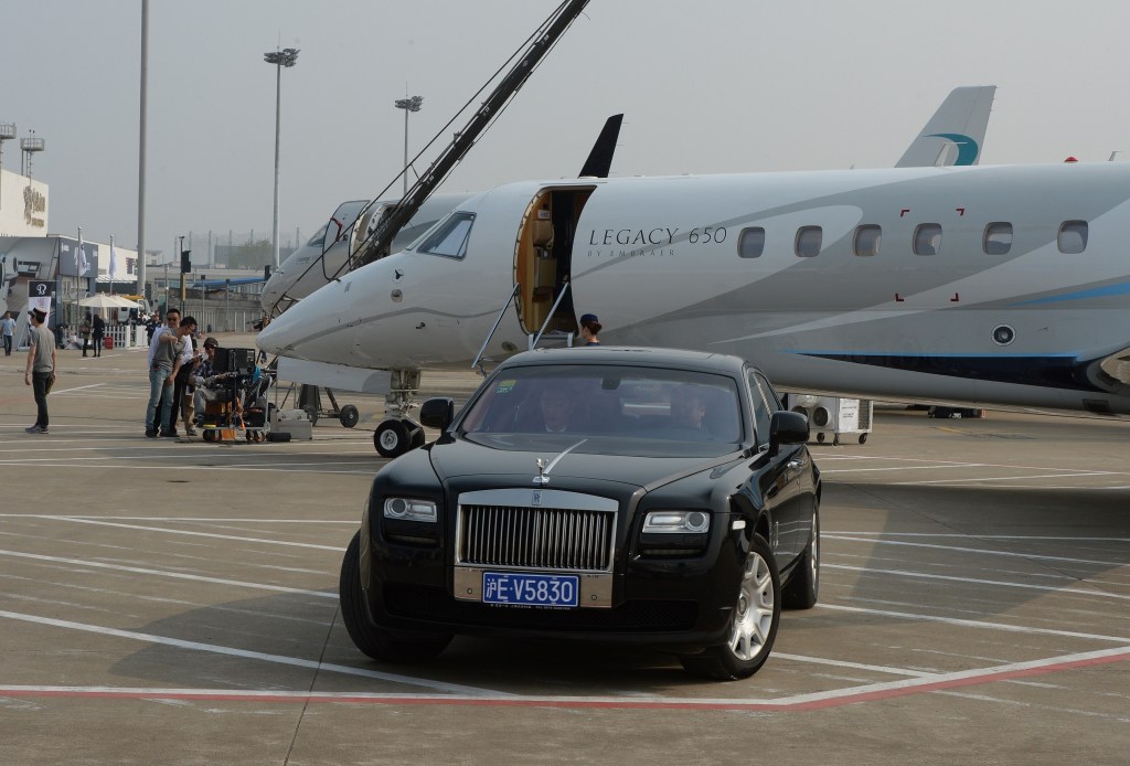 A black Rolls Royce in front of a private jet