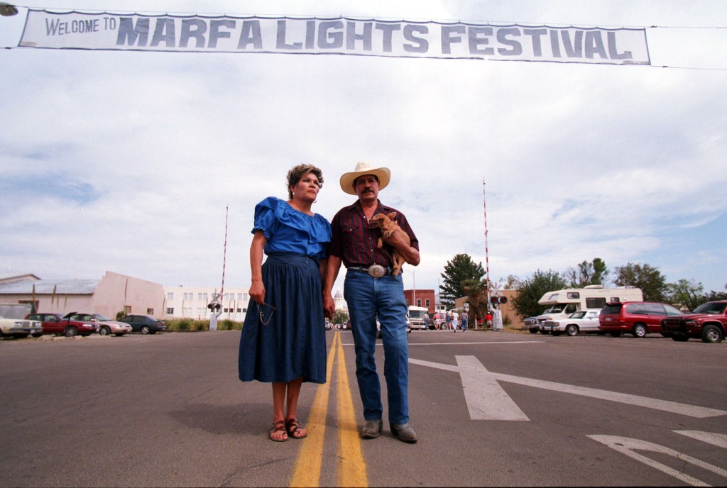 A couple standing under the Marfa Lights festival banner during the yearly marf lights festival. 