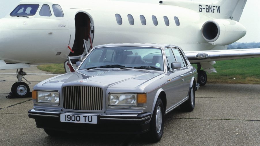 A Bentley Turbo R sits beside a private jet on a runway