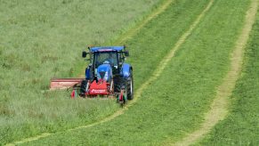 a new holland tractor cutting a hay field