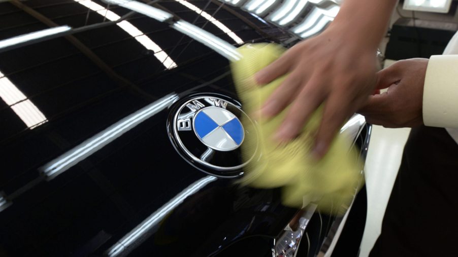 A man polishes the hood of a black BMW