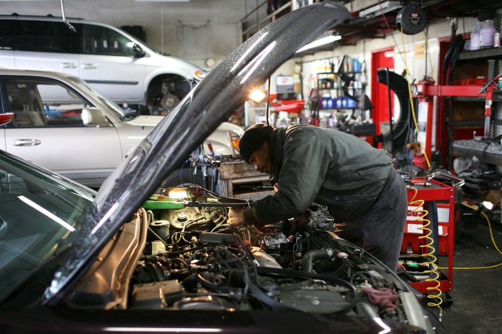 A mechanic works on the engine of a car