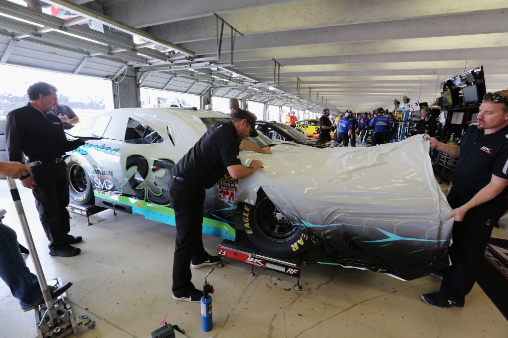 NASCAR team members apply a car wrap to one of their vehicles