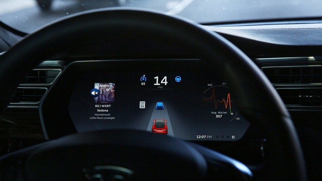 The in-dash display of a Tesla shows Autopilot adaptive cruise software in use