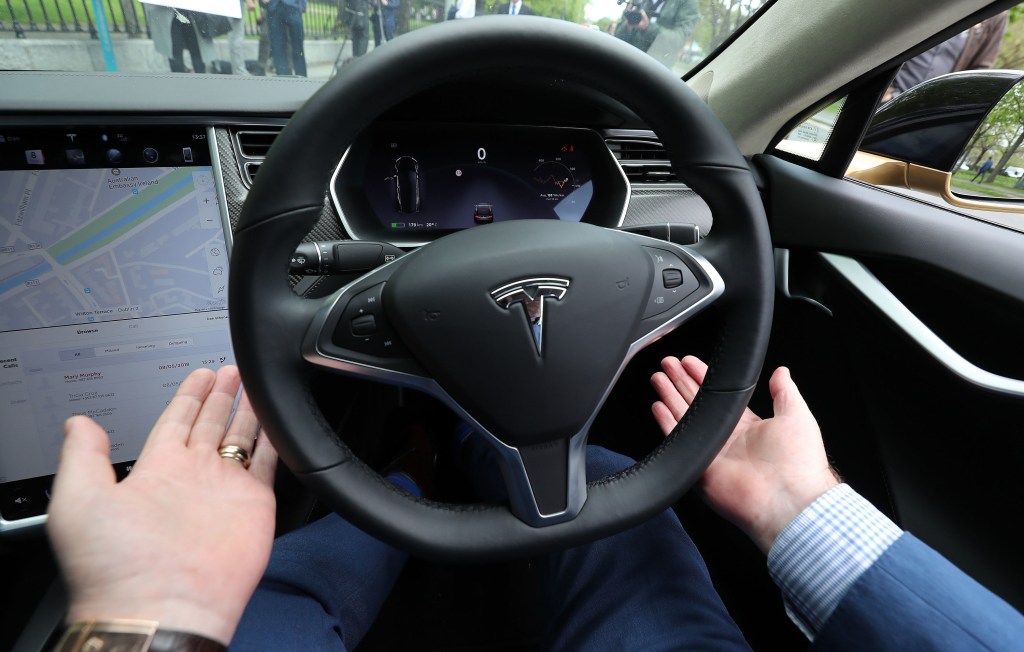 A man rides in a Model S with his hands off the wheel, letting the car drive for him