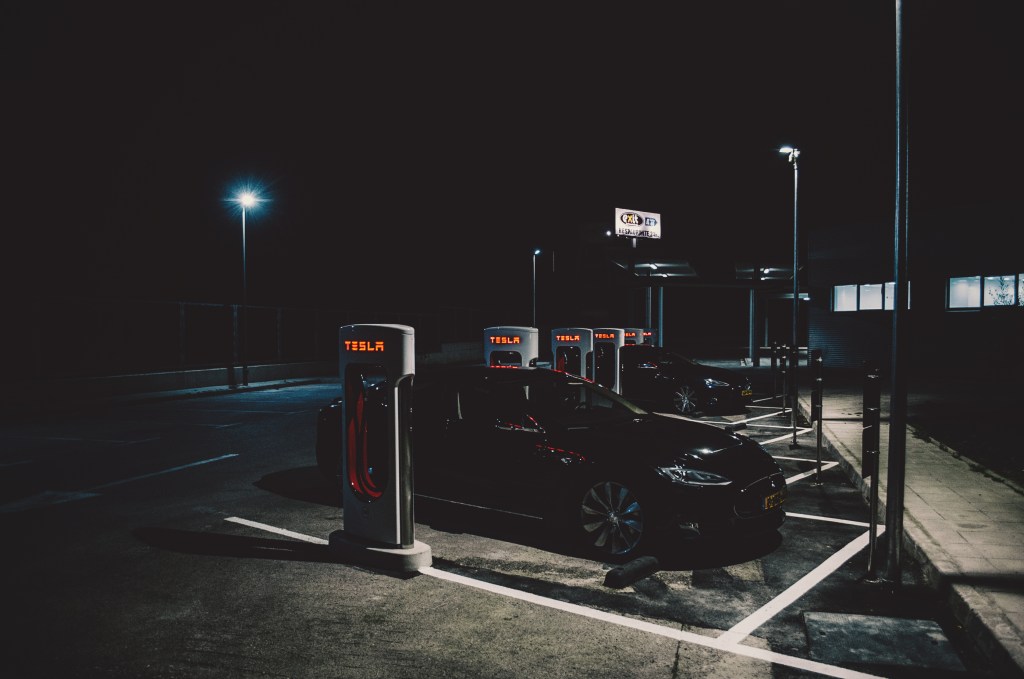 A black Tesla Model S sedan charging on a dark street in Barcelona