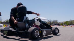 A man coaching a child on how to properly operate a go-kart
