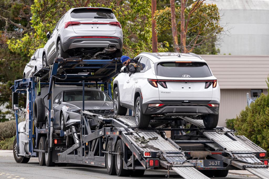 A worker unloads a Hyundai vehicle off of a transporter truck at a car dealership in Richmond, California, in July 2021