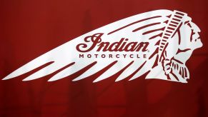 A white Indian Motorcycle logo on a red background with some vague shadows behind it.