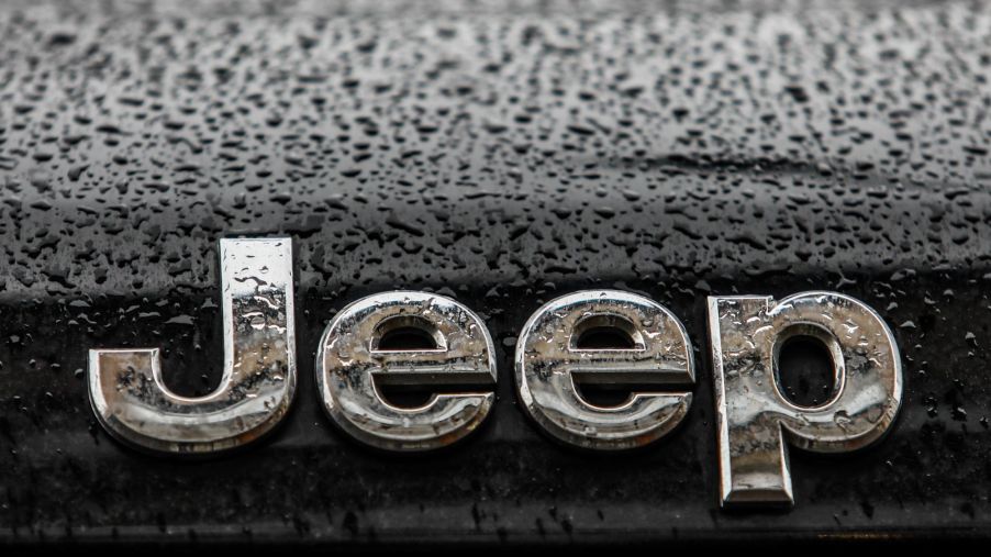 Jeep's logo in silver on a black car with raindrops