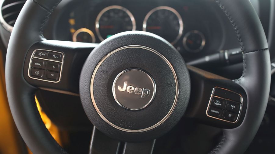 A black Jeep steering wheel with the name printed in the center. The background is the gauge cluster.
