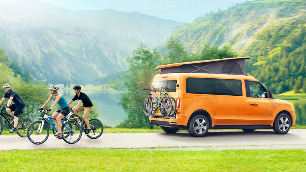 Tiny camper van with family cycling behind it