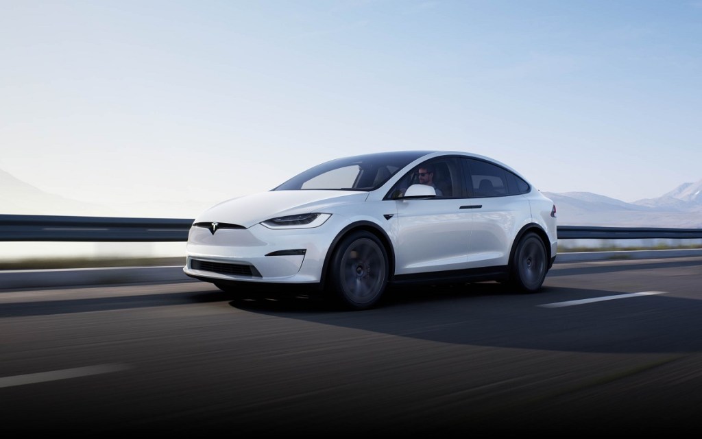 A white 2021 Tesla Model X driving down a highway.