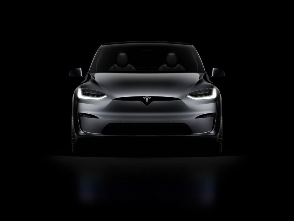 A dark gray 2021 Tesla Model X against a black background. 