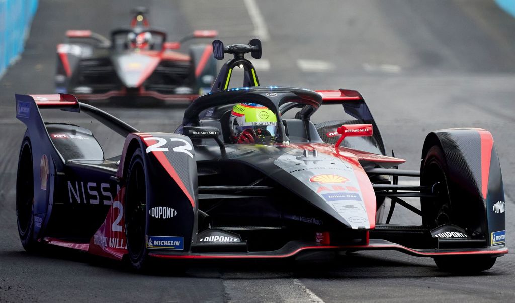Nissan's black Formula E Racer coated in sponsor advertisements and logos driving around the track.