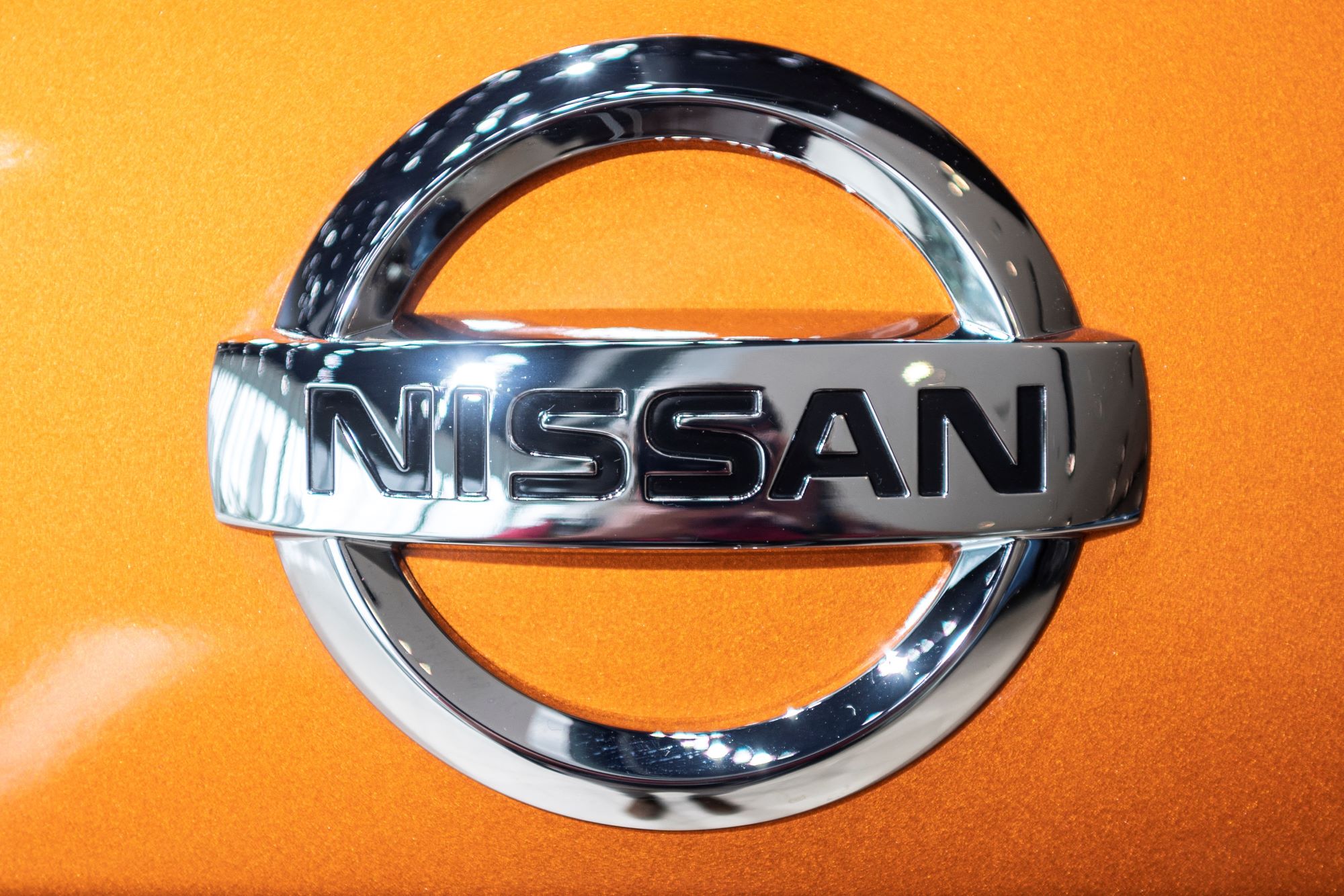 Close-up of chrome Nissan logo on an orange car