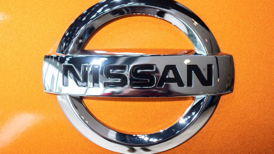 Close-up of chrome Nissan logo on an orange car