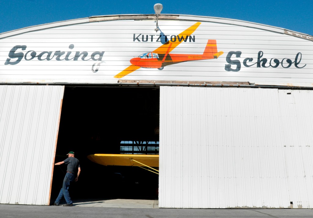 Thomas B. Edelstein of Fleetwood, the airport's licensed airplane mechanic, closes the main hangar doors, hiding a yellow 1940's Piper Cub. When you own a plane, you will need a place to store it