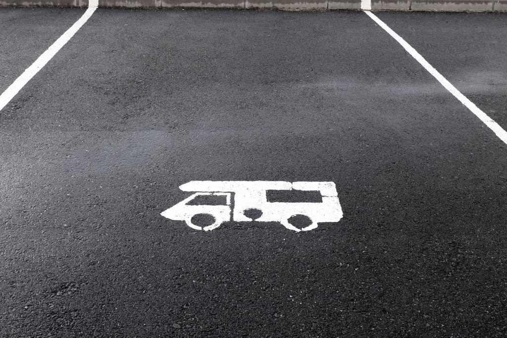 A blacktopped parking space with a white stencil sprayed representation of an RV.