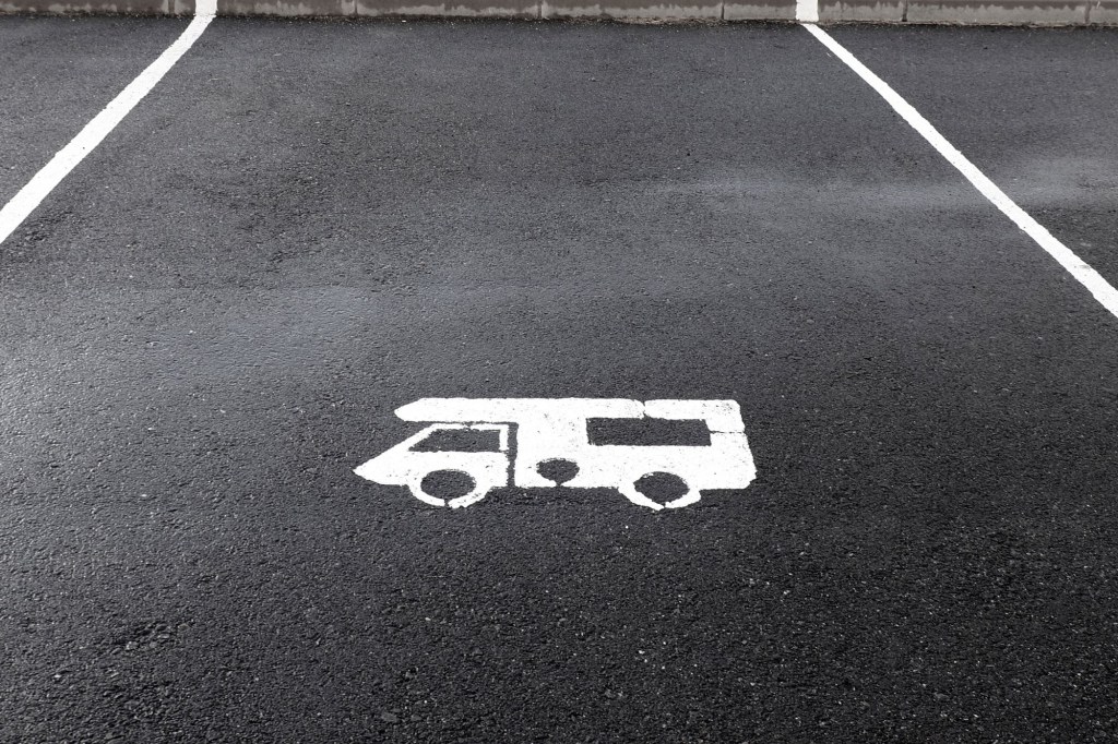 A blacktopped parking space with a white stencil sprayed representation of an RV.