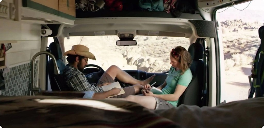A man and woman sit inside a Ram Promaster City Wagon writing in notebooks.