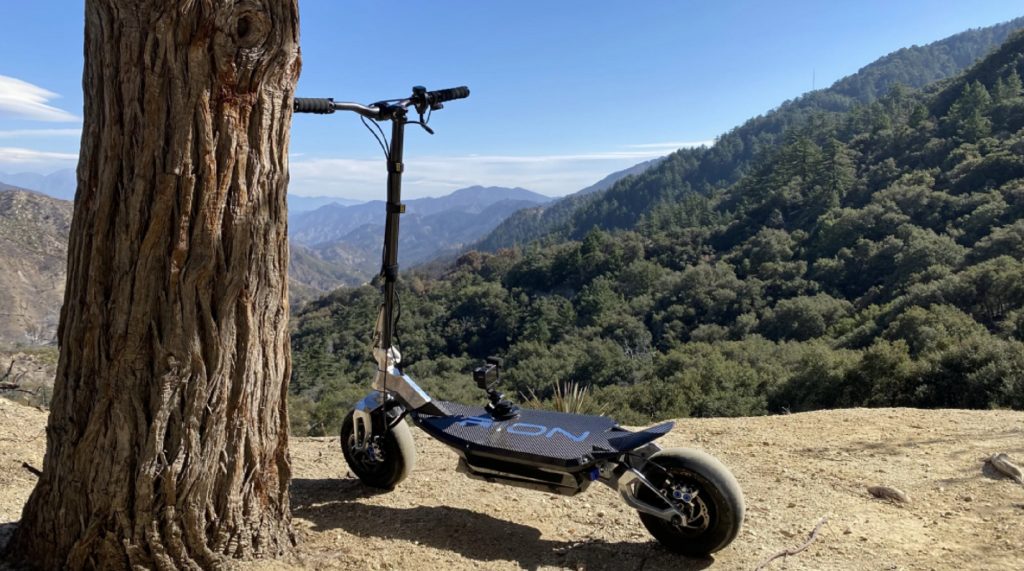 The rear 3/4 view of the carbon-fiber-and-aluminum Rion Thrust electric motorized scooter on a rocky hill