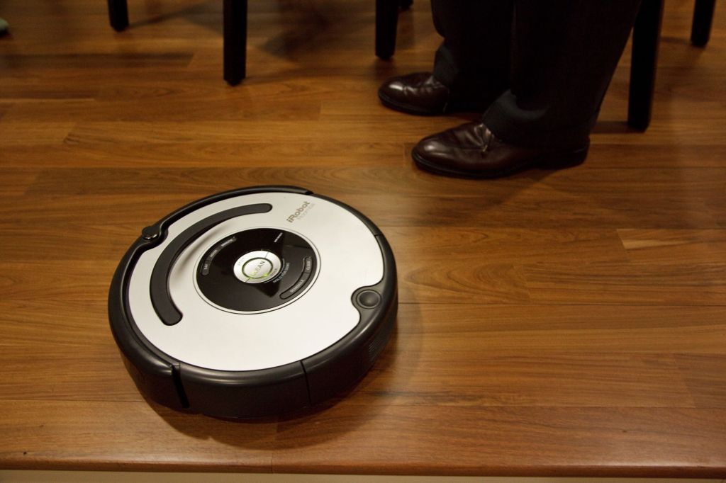 A Roomba autonomous vacuum cleaner on a wooden floor