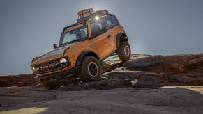 A yellow 2021 Ford Bronco off-roading over rocks