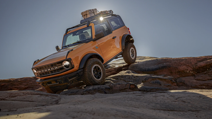 A yellow 2021 Ford Bronco off-roading over rocks