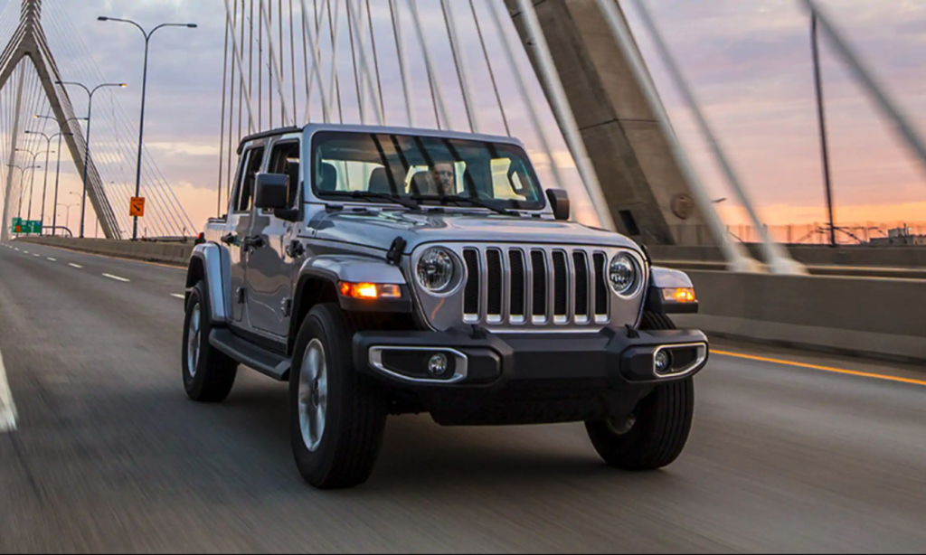 The 2021 Jeep Wrangler 4xe driving over a bridge at sunset