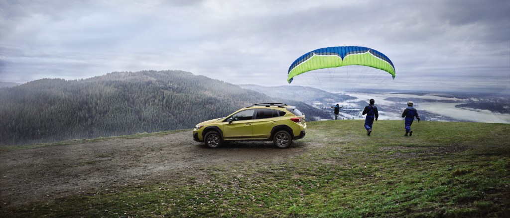 Subaru Crosstrek parked on a cliff as a hang glider takes off