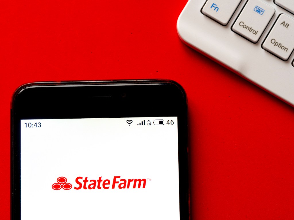 An iPhone sitting on top of a desk with the StateFarm logo shown on the screen, StateFarm is one of the cheapest car insurance companies