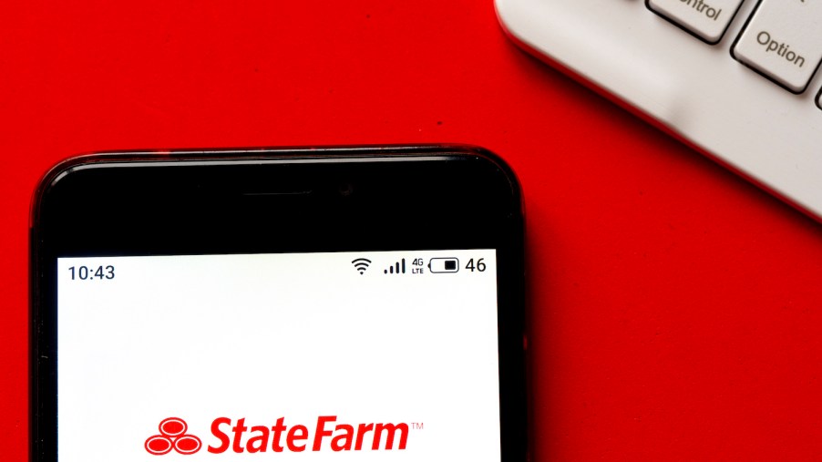 An iPhone sitting on top of a desk with the StateFarm logo shown on the screen, StateFarm is one of the cheapest car insurance companies