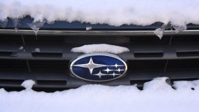 A snow-covered Subaru logo badge on the front grille of a car