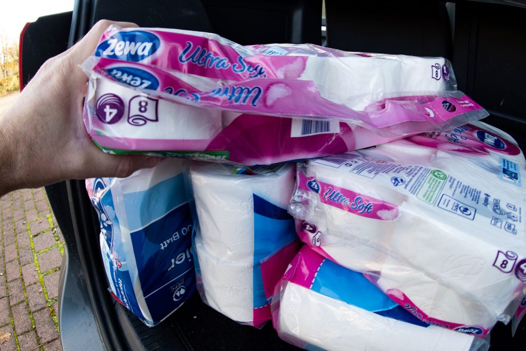 Packages of toilet paper being unloaded from a car trunk