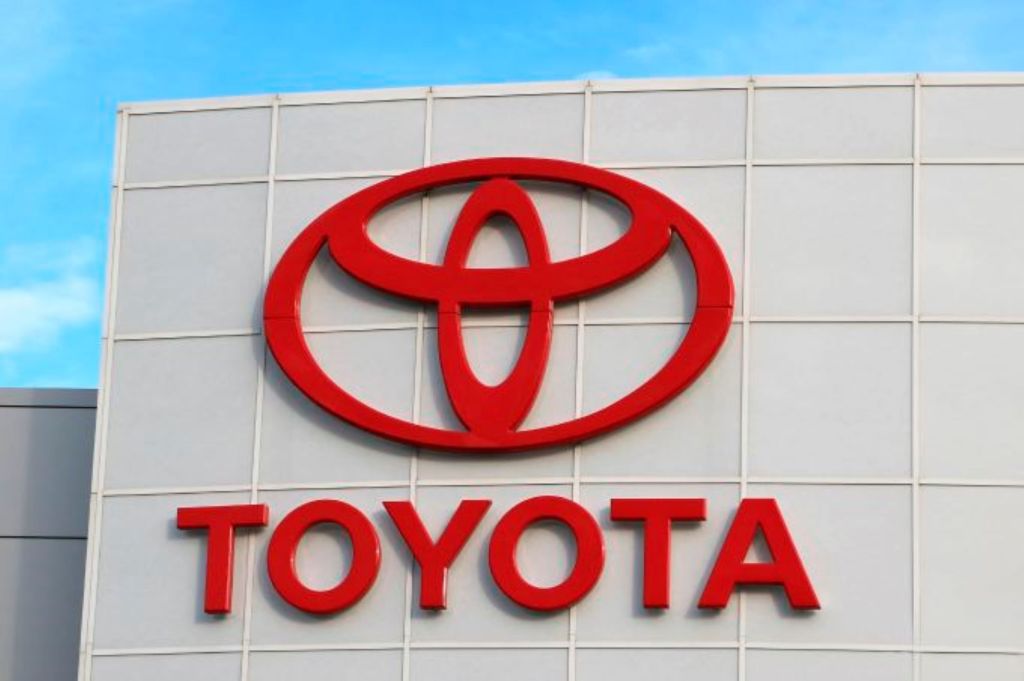 Closeup of Toyota's logo in red on the front of a ivory building with 'Toyota' written underneath it.