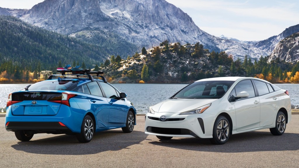 two Toyota Prius models parked near a lake in the mountains 