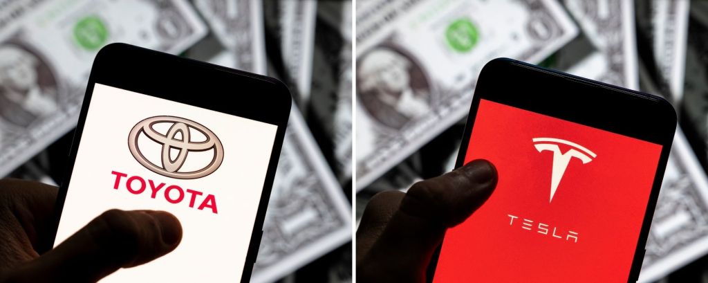 The Toyota and Tesla logos on smartphones with a background of dollar bills