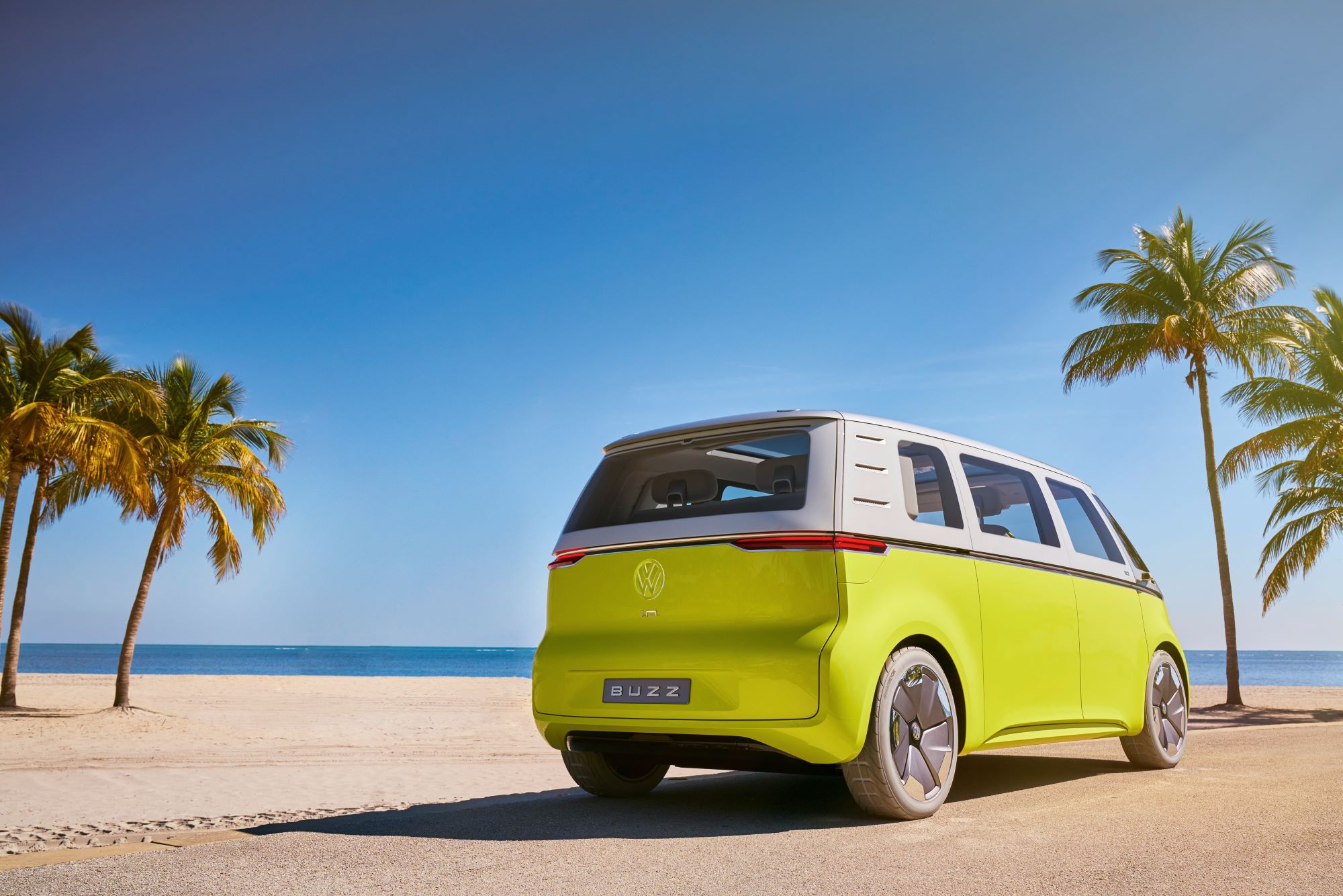 The Volkswagen ID. Buzz Concept in yellow and white parked on a tropical beach near palm trees
