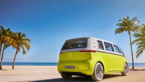 The Volkswagen ID. Buzz Concept in yellow and white parked on a tropical beach near palm trees