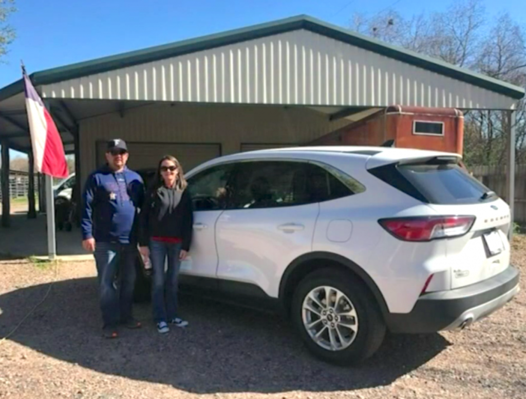 Walker and husband with her new Ford Escape in front of house