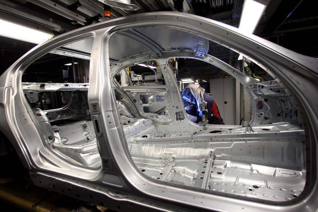 A man attaches a door to the car body on the BMW 3-series production line.