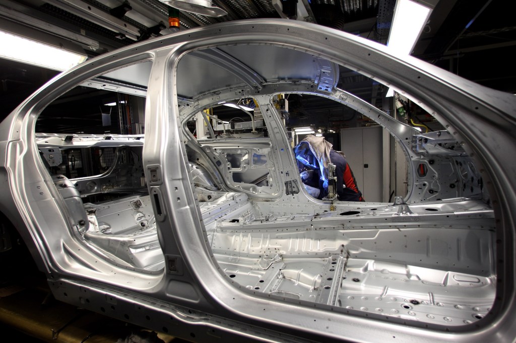 A man attaches a door to the car body on the BMW 3-series production line. 