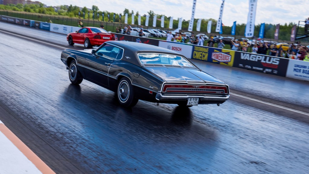 A brown and red muscle car racing during the event.