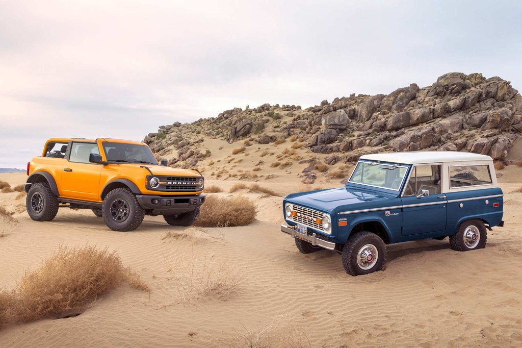 A new Cyber Orange Bronco posed with a classic one on a sand dune