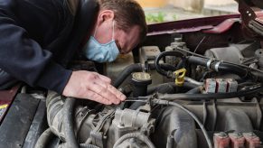 A mechanic wearing checks a car engin