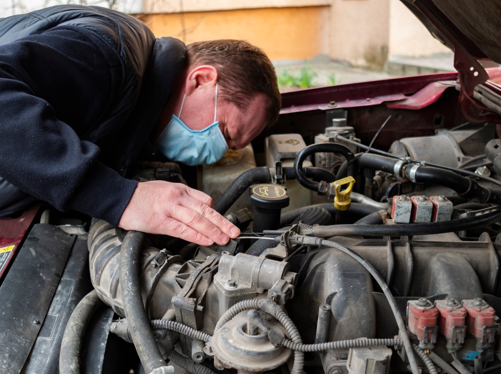 A mechanic wearing checks a car engine