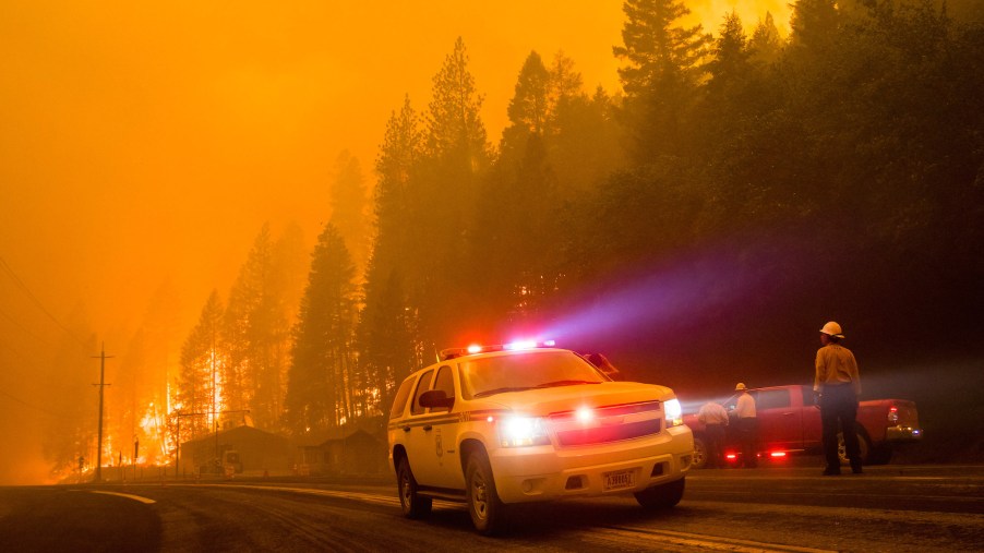 Firefighters block the road as a forest fire reaches a highway in California